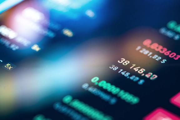 Close up view of a digital trading platform displaying live market prices, financial figures, and trading data with colourful illuminated indicators, representing real time market monitoring and investment analysis.