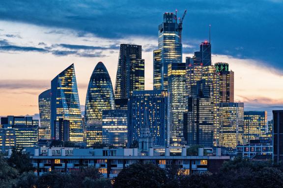 City of London skyline at dusk with illuminated skyscrapers and modern financial district buildings.