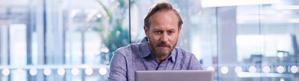 Focused professional man working on laptop in a modern office environment