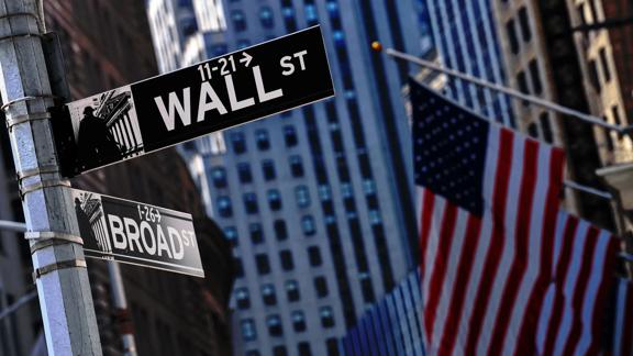 Wall Street and Broad Street intersection sign with American flags in New York City.