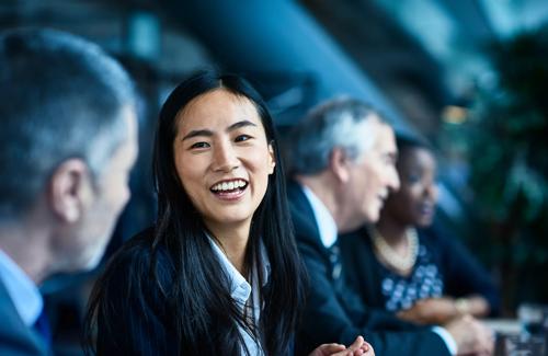 Woman smiling and talking with colleagues during a meeting in a modern office setting