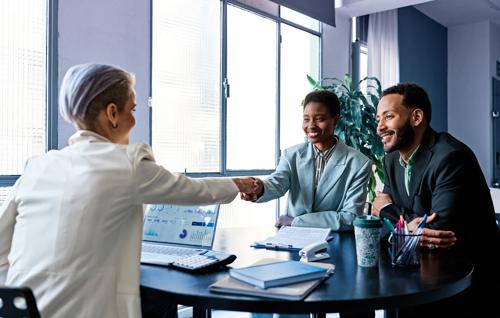 Business professionals shaking hands in a modern office, symbolizing successful account opening and partnership.

