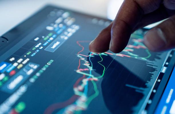 A close-up of a hand touching a tablet computer displaying a financial market graph