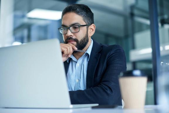 Financial professional analyzing market information on a laptop in a contemporary office setting