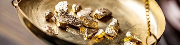 Gold nuggets and bars in a bowl, symbolizing precious metals, wealth, and global commodities trade
