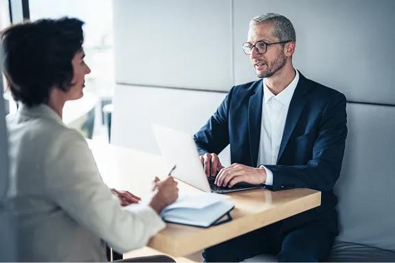 Duas pessoas em reunião de negócios, utilizando notebook sobre mesa