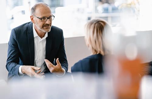 Business professional in a suit having a one-on-one discussion with a colleague in a modern office setting