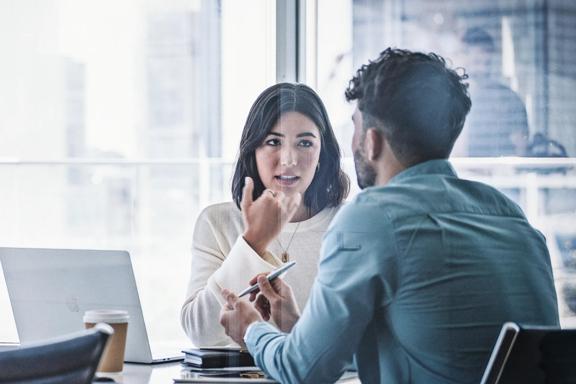 Two professionals having a discussion in front of a laptop in modern office