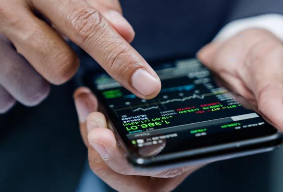 Close-up of a person using a smartphone to analyze stock market data and financial charts
