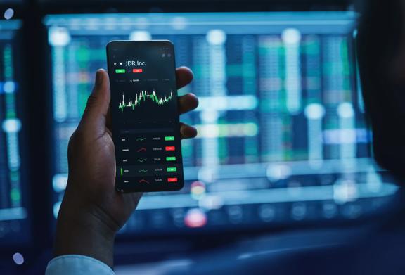 Man holding mobile phone showing financial chart