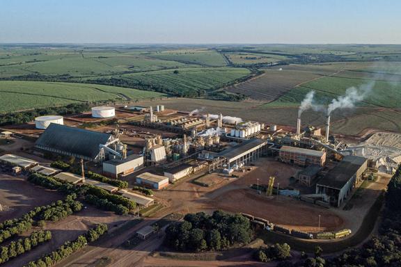 Vista aérea de grande usina de processamento agrícola cercada por plantações de cana-de-açúcar
