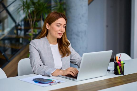 Professional workspace with a laptop, desk accessories, and a person typing.