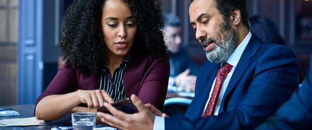 Businesswoman and businessman reviewing information on a mobile phone during a meeting