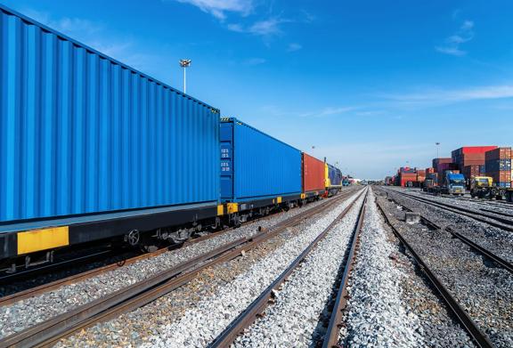 Contêineres de carga alinhados em um trem de carga em um pátio ferroviário.