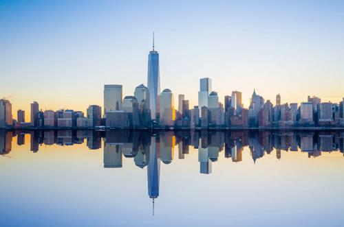 Panoramic view of New York City skyline at sunset featuring the Empire State Building and surrounding skyscrapers
