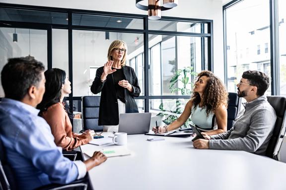 Executiva conduzindo apresentação de reunião para equipe diversa em escritório moderno
