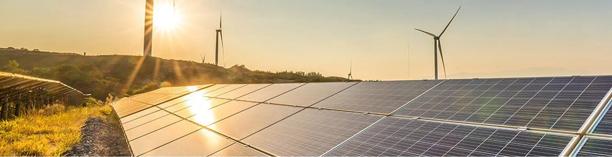 Solar panels and wind turbines generating renewable energy at sunset on a hillside