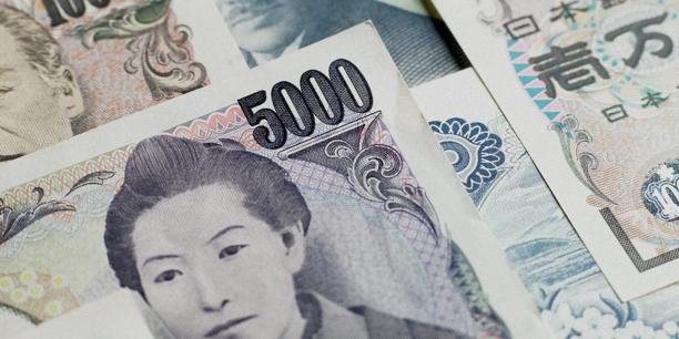 Close-up of several Japanese yen banknotes overlapping, with the number “5000” prominently visible on one note in the foreground.