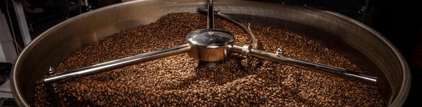 Close-up of roasted coffee beans being processed, symbolizing coffee industry and trade