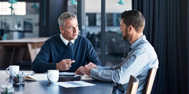 Business meeting with two people discussing documents at a table in a contemporary office.