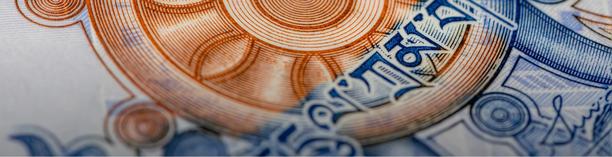 Macro close-up of a banknote showing intricate orange and blue security patterns and detailed engraved linework.