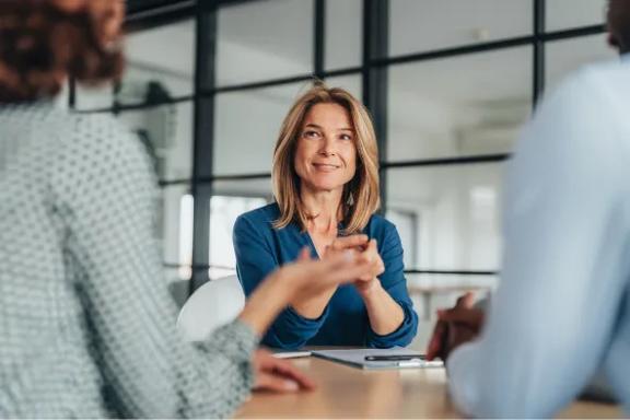Focused businesswoman in formal attire talking to colleagues in a modern office setting