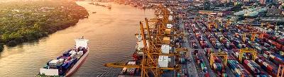 Boat with shipping containers on river at sunset