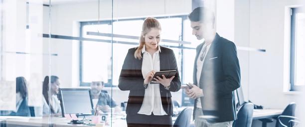 Business professionals collaborating with a tablet in a modern glass-walled office