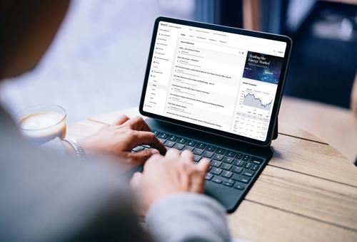Pessoa usando um tablet com teclado para analisar dados e gráficos de mercado em uma cafeteria.