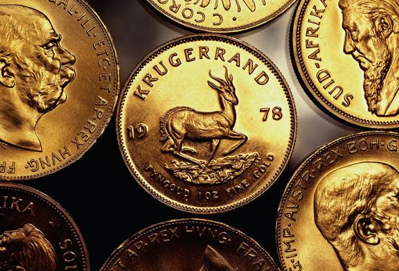 Close-up of South African Krugerrand gold coins featuring a springbok antelope and historical figures