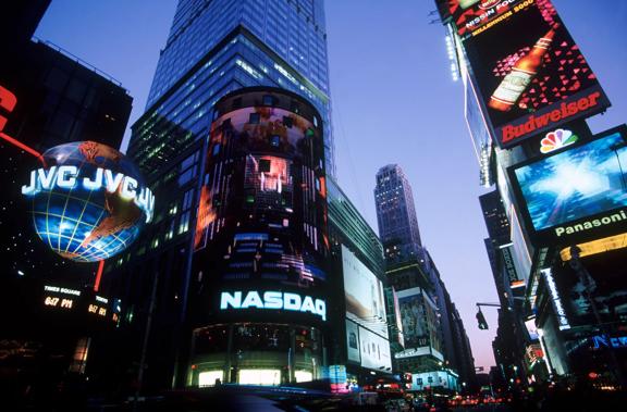 Times Square at night with illuminated billboards and the NASDAQ building in New York City.