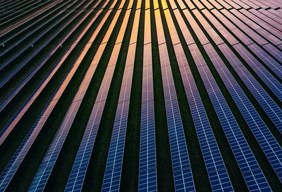 Fileiras de painéis solares capturando a luz do sol em uma fazenda de energia renovável em grande escala ao pôr do sol