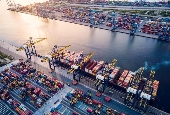 Aerial view of a busy shipping port with cargo containers, cranes, and docked container ships