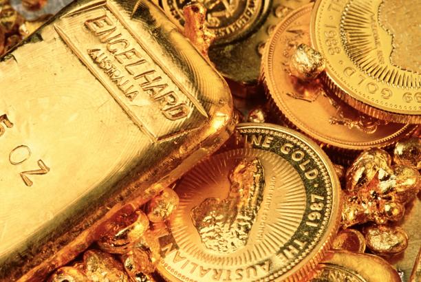Close-up view of gold bars, gold coins, and raw gold nuggets arranged together.